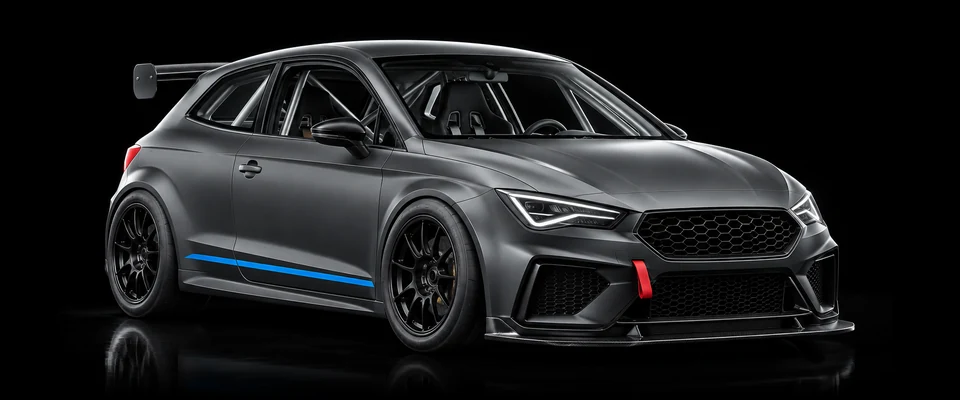 Mattgrauer Rennwagen mit Überrollkäfig, Heckflügel und Abschleppschlaufe im schwarzen Studio.